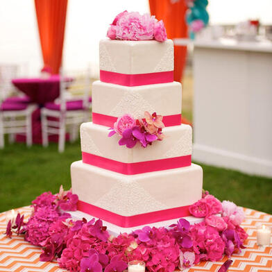 Γαμήλια τούρτα με λουλούδια στη βάση της.